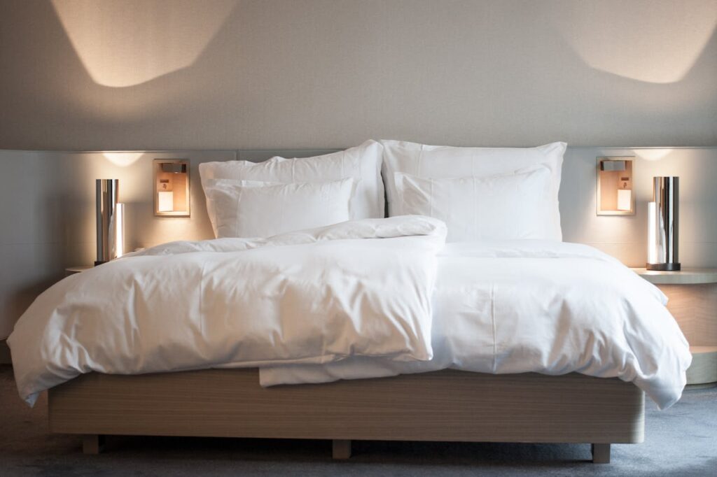 Demo Post 1 Elegant hotel room with comfortable bedding and modern lighting fixtures.